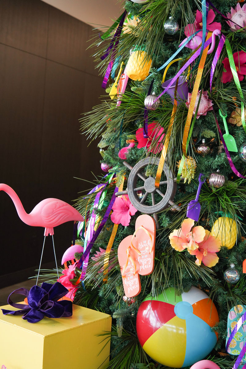 A festive Christmas tree decorated with colorful ribbons and a playful flamingo ornament.
