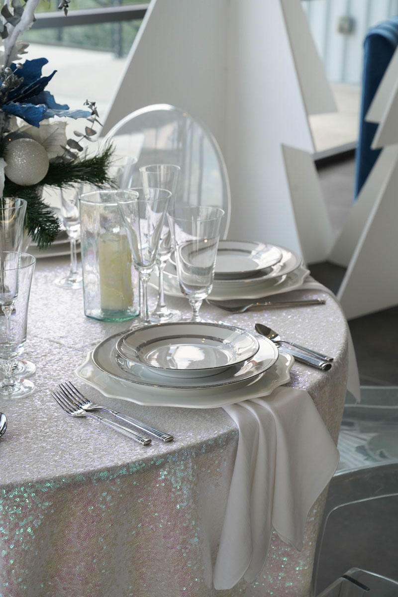A table covered with a white tablecloth, elegantly set for a meal.